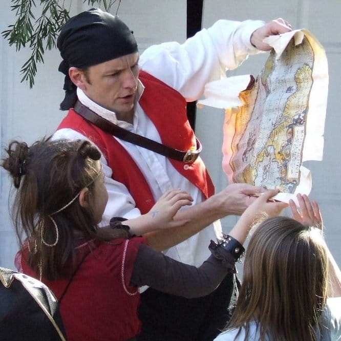 Capt'n Kenny the Irish Pirate inspects his treasure map with young buccaneers at kids parties in Sydney